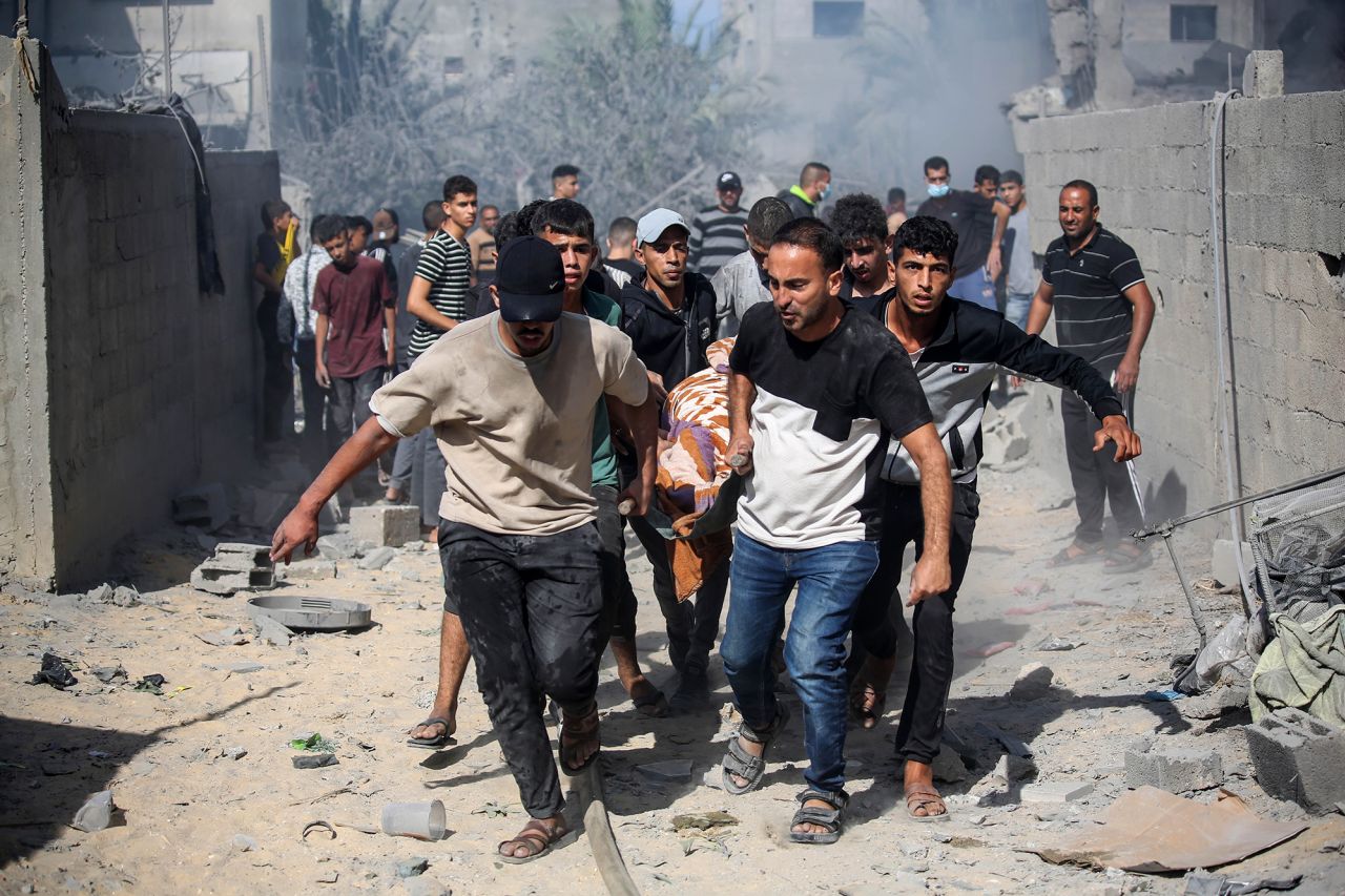 Palestinians carry a victim of Israeli air raids in southern Gaza on October 18, 2023.