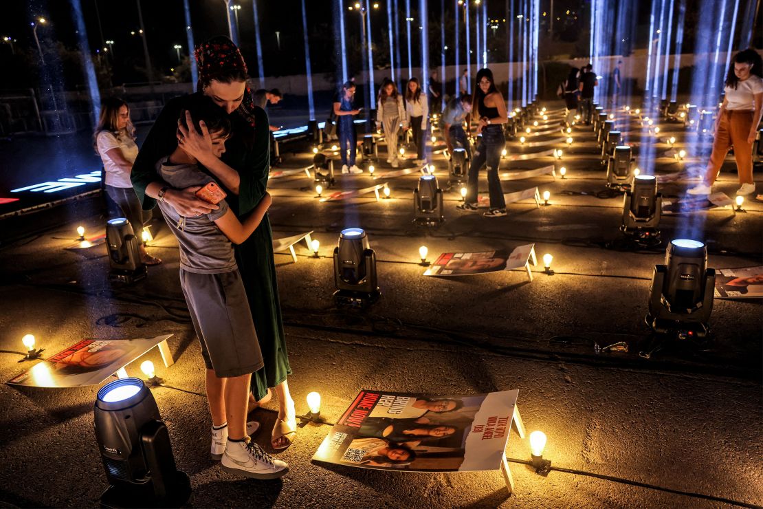 A woman embraces a child while standing between posters of hostages abducted by Hamas militants during the October 7 attack and currently held in the Gaza Strip.