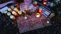Velas dejadas por los participantes sobre un cartel en el que se lee: "Contra el antisemitismo".