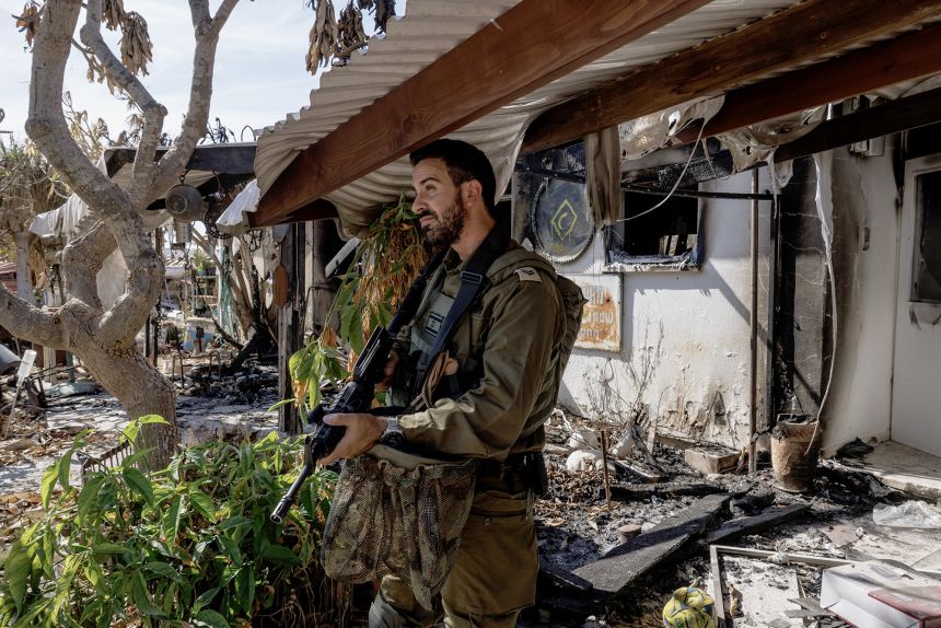 Bir asker, 30 Ekim 2023'te Nir Oz Kibbutz'unda yanmış bir evi inceliyor.