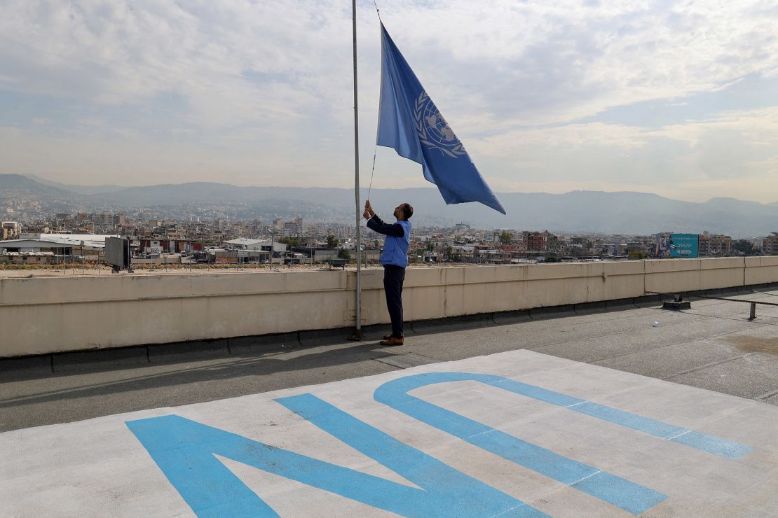 An employee at the United Nations Relief and Works Agency (UNRWA) lowers the UN flag on the roof of the organization's regional offices in the Lebanese capital Beirut on November 13, 2023.