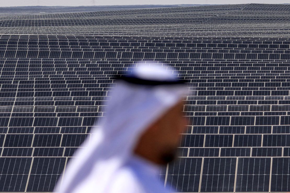 A man stands in front of photovoltaic panels at al-Dhafra Solar Photovoltaic (PV) Independent Power Producer (IPP) project south of Abu Dhabi on November 13, 2023.