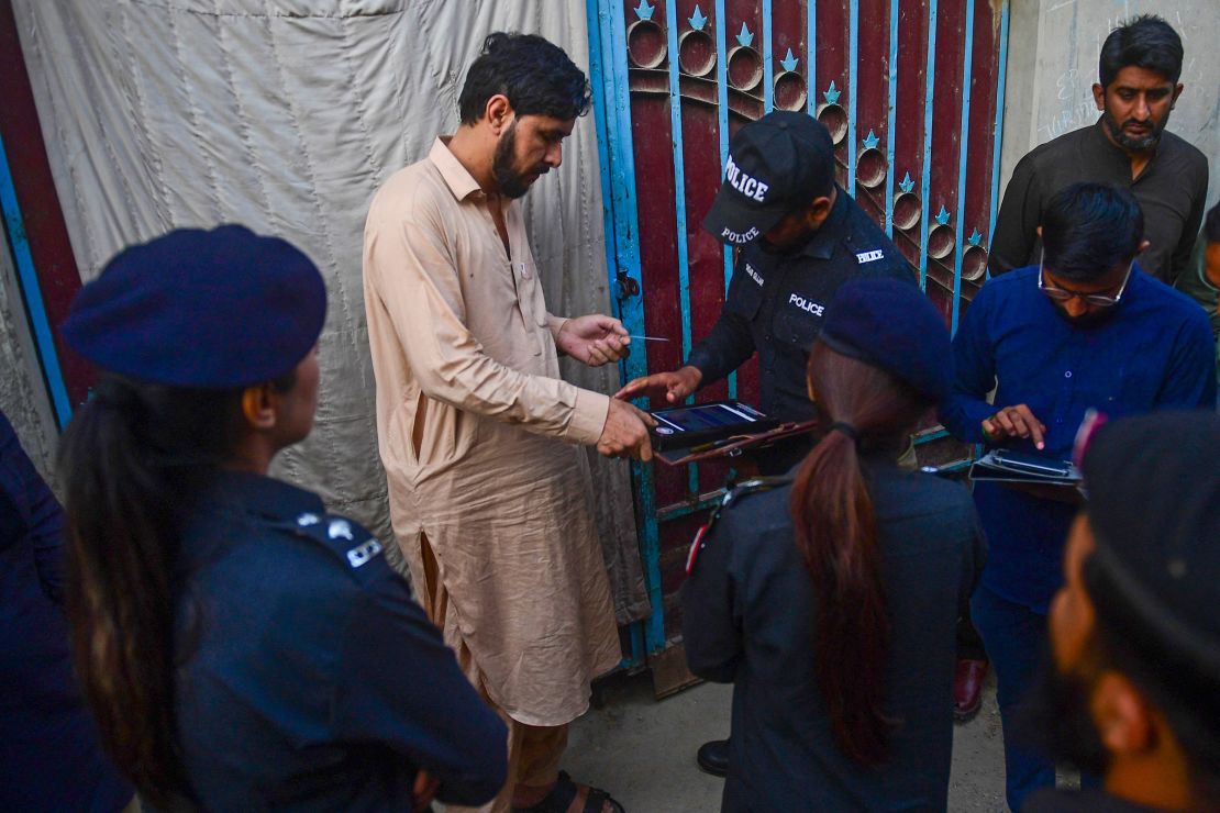 Police test the biometrics of an Afghan refugee during a search operation to identify undocumented immigrants, on the outskirts of Karachi on November 17, 2023.