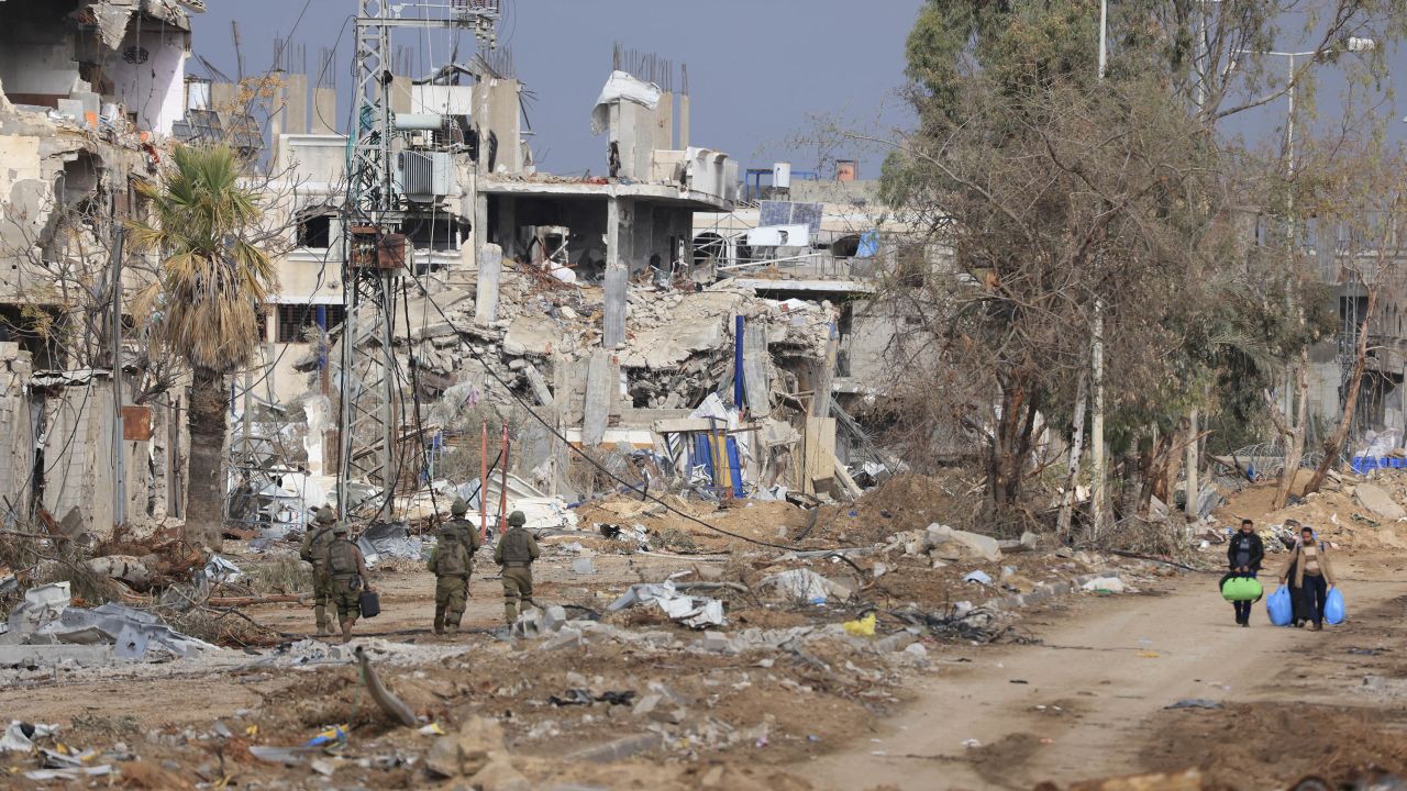 Israeli soldiers walk past Palestinians fleeing the north along the Salaheddin road in the Zeitoun district on the southern outskirts of Gaza City on November 28, 2023. A truce between Israel and Hamas entered a fifth day on November 28 after the deal was extended to allow further releases of Israeli hostages and Palestinian prisoners. (Photo by MAHMUD HAMS / AFP) (Photo by MAHMUD HAMS/AFP via Getty Images)