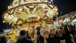 Visitors take photos in front of the carrousel at the Dresden Striezelmarkt on the day of its opening in Dresden, eastern Germany on November 29, 2023. Every year, the Striezelmarkt attracts around three million visitors. The first Striezelmarkt took place in 1434 and this year it will be held for the 589th time, making it the oldest Christmas market in Germany. It will be open until December 24. Among the attractions is the 14,61 meter tall Erzgebirge (Ore Mountains) step pyramid and the reportedly world's largest walk-in Schwibbogen candle-holder. (Photo by JENS SCHLUETER / AFP) (Photo by JENS SCHLUETER/AFP via Getty Images)