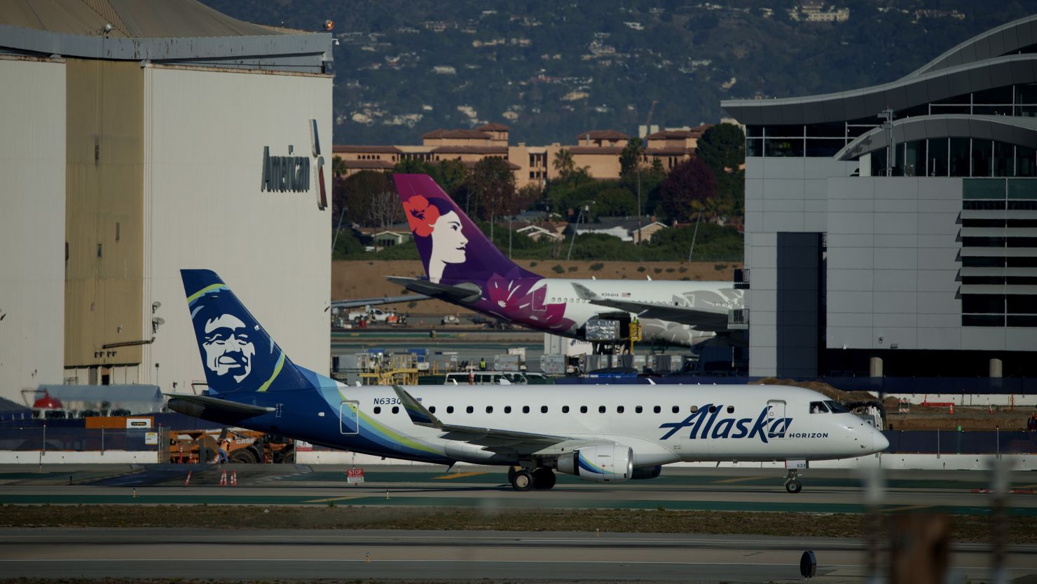 An Alaska Airlines and a Hawaiian Airlines airplane at Los Angeles International Airport (LAX) in Los Angeles, California.