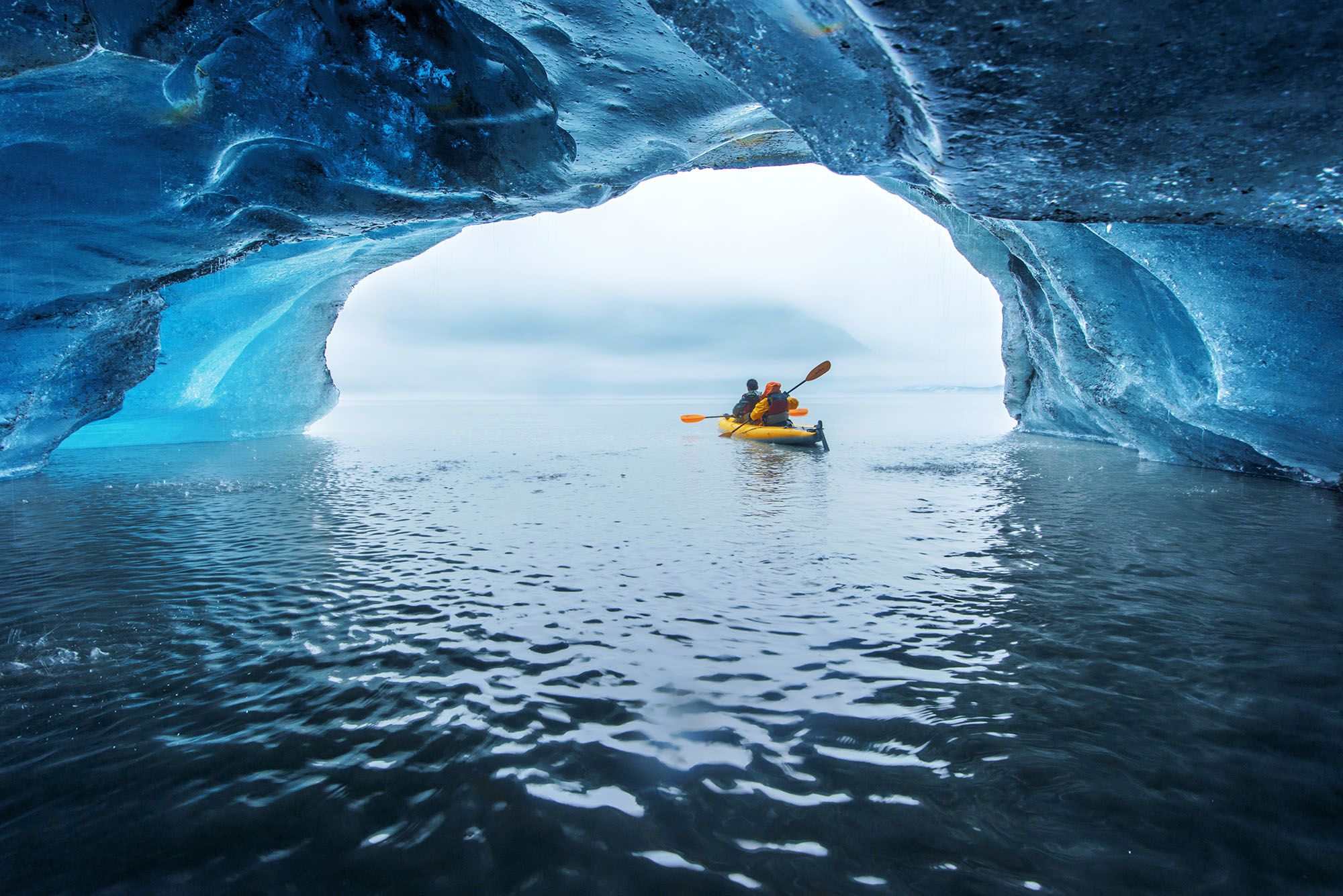 Tourist kayaking inside a floating iceberg from the Valdez Glacier in Alaska.