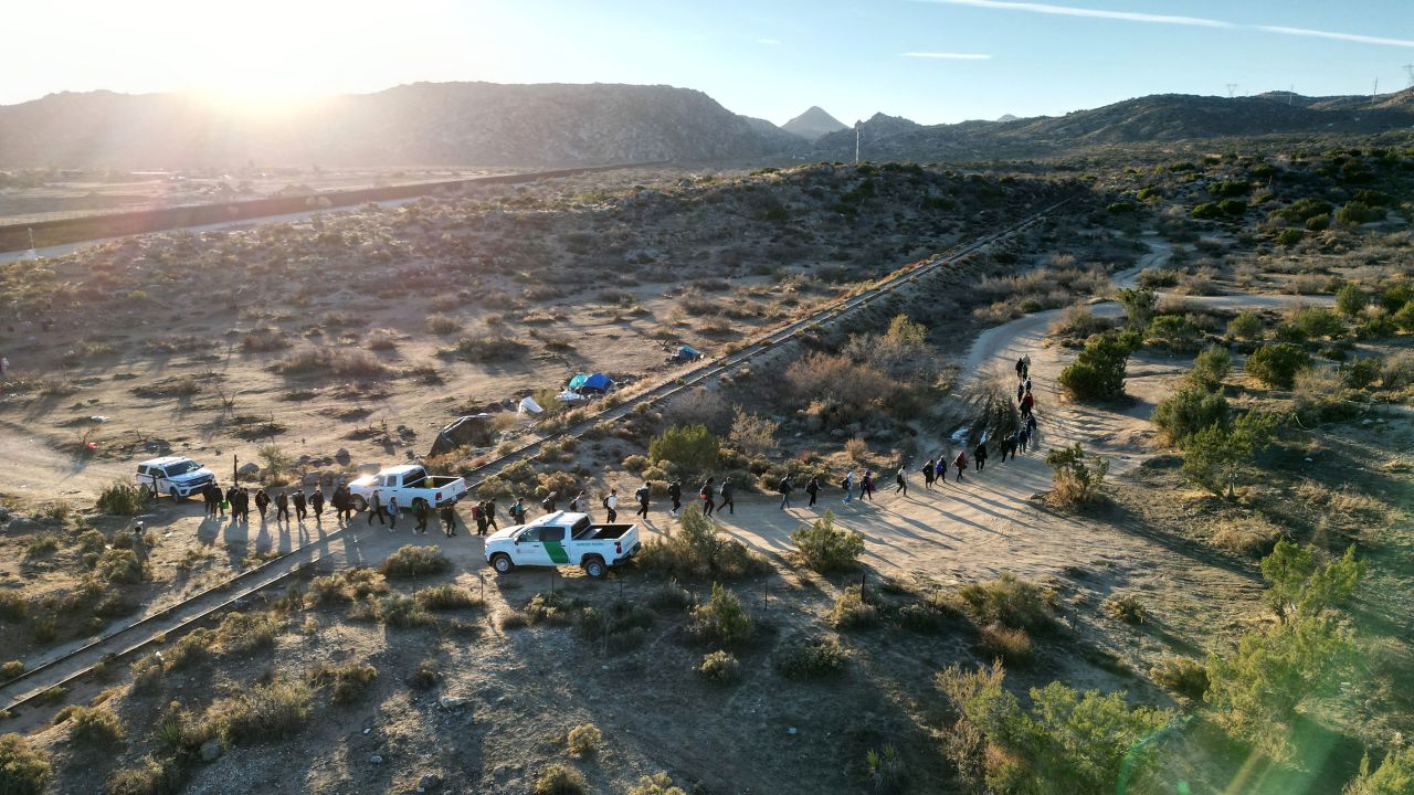 Border patrol agents lead migrants who entered the US illegally to a port of entry in Jacumba, California, on December 6, 2023.