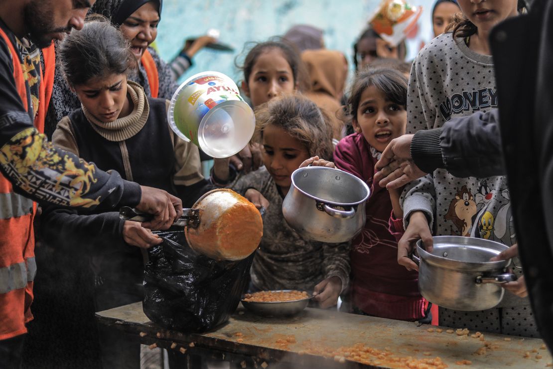 Displaced Palestinians gather to collect food cooked by volunteers in Rafah on December 9, 2023.