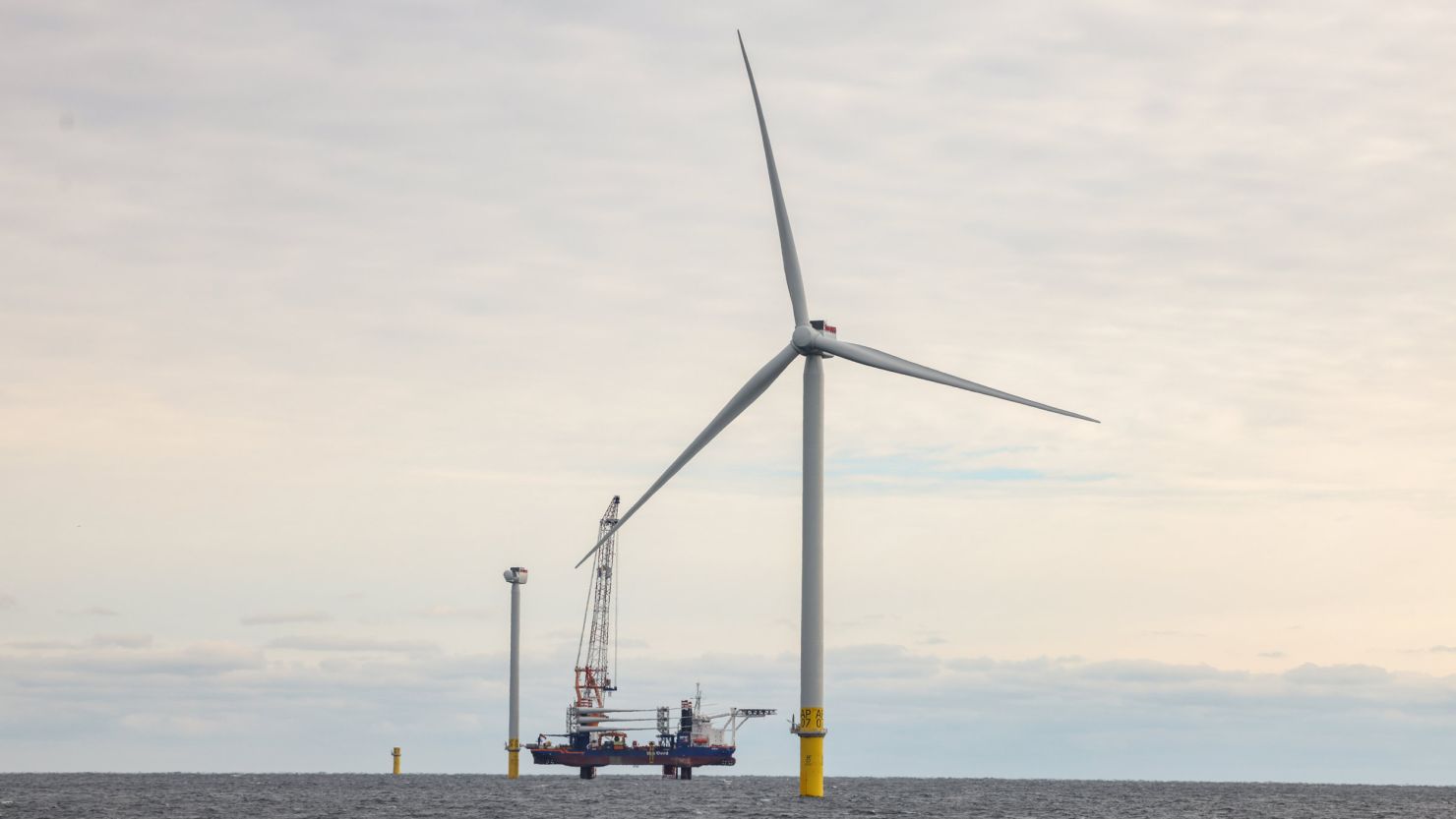 An operational wind turbine, two more under construction and a lifting barge at the South Fork Wind Farm in the Atlantic Ocean, on December 7, 2023.