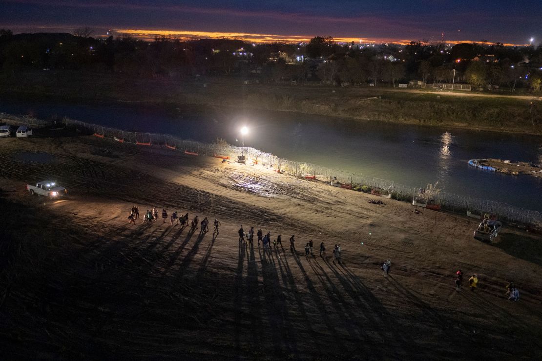 Migrants who had crossed the Rio Grande from Mexico walk towards a processing center in Eagle Pass, Texas, on December 18, 2023.