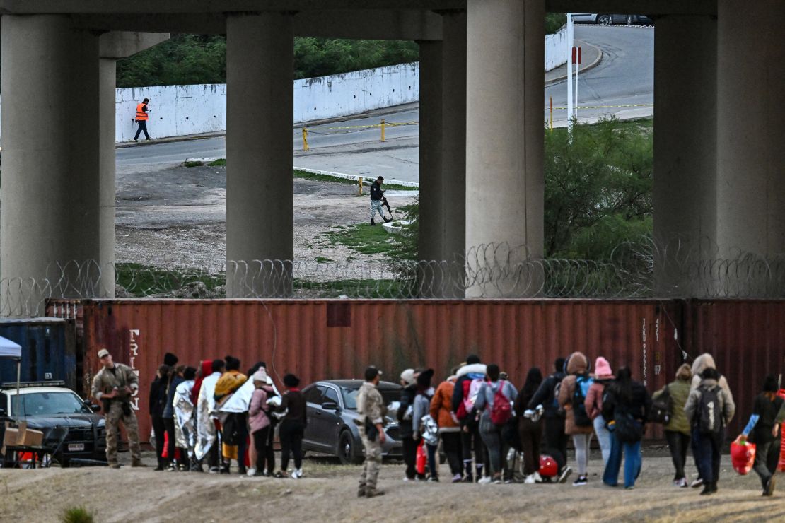 A Mexican security guard is seen across the border in Piedras Negras, a city in Mexico, as immigrants wait to be processed at a U.S. Border Patrol transit center after crossing the border in Eagle Pass, Texas, December 22, 2023.