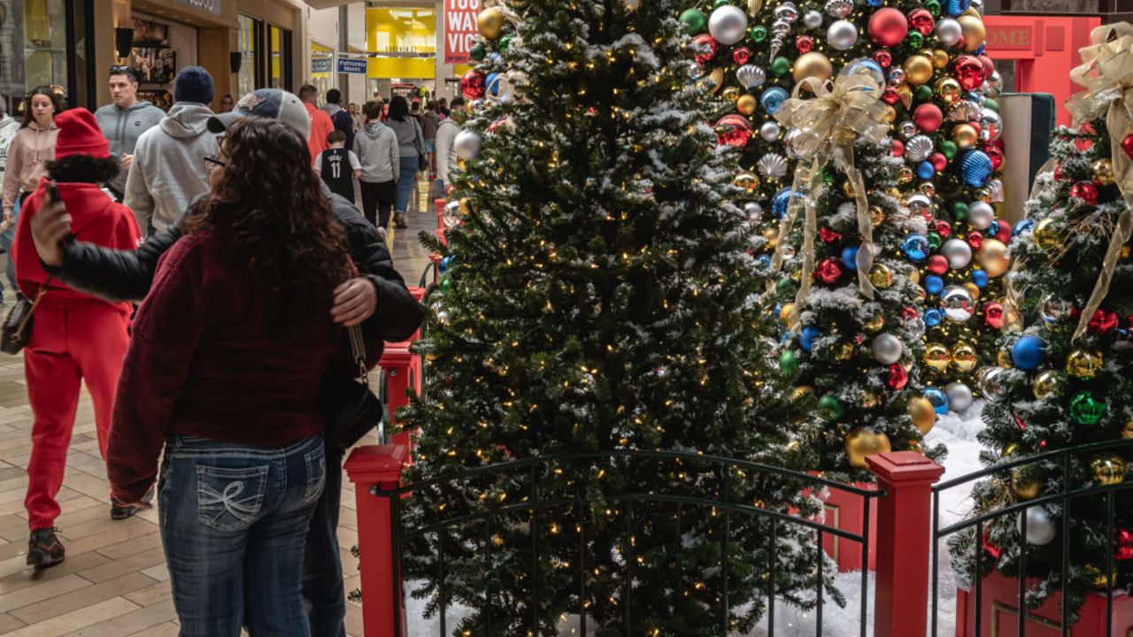 LOUISVILLE, KENTUCKY - DECEMBER 22: Shoppers pose for a selfie in front of Christmas trees at the St. Matthews Mall on December 22, 2023 in Louisville, Kentucky. (Photo by Jon Cherry/Getty Images)