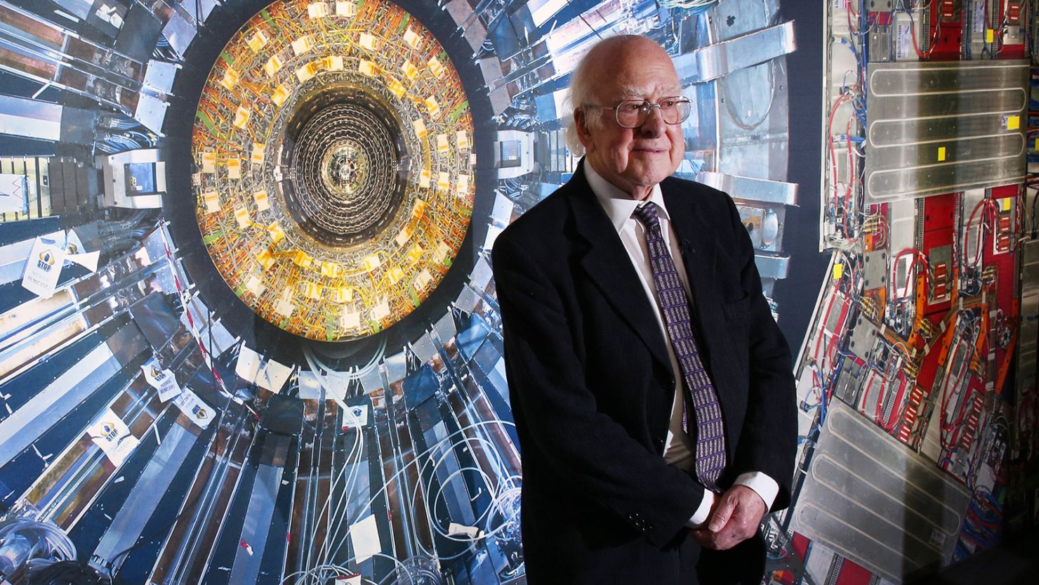 The late physicist Peter Higgs stands in front of a photograph of the Large Hadron Collider at the Science Museum's "Collider" exhibition in November 2013, in London.