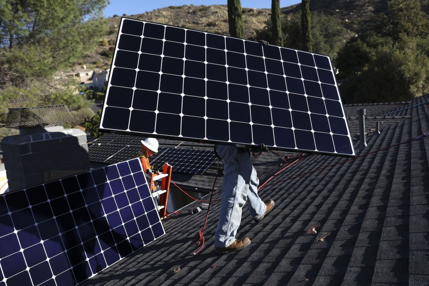 Workers install solar panels on the rooftop of a home in Poway, California, on Tuesday, Dec. 5, 2023.