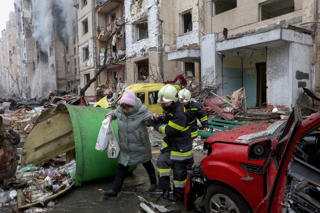 Firefighters evacuate a woman from a destroyed multi-story building after a missile attack in central Kyiv.