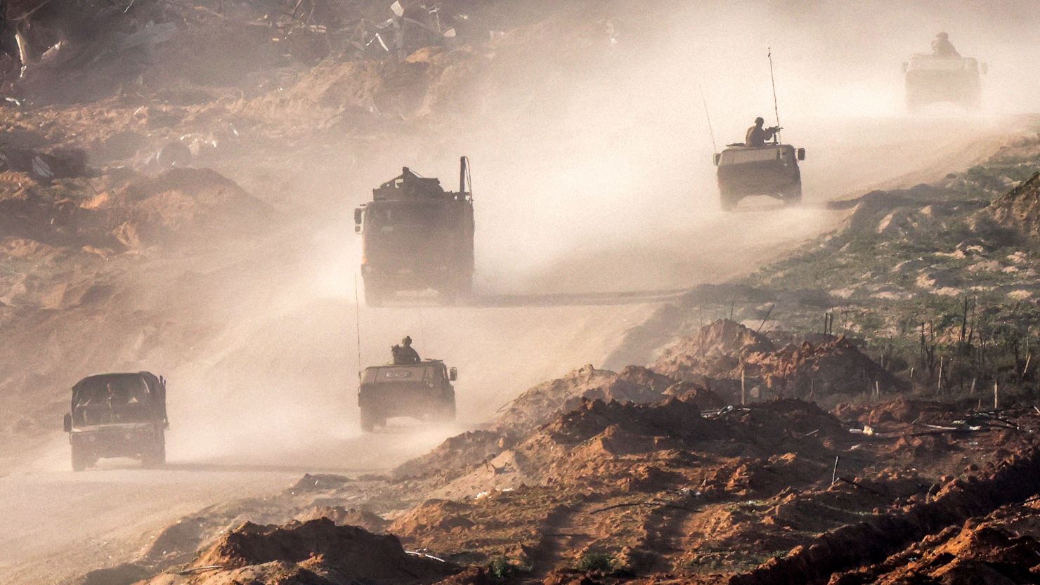 Israeli army vehicles move along a dirt road in the Gaza Strip near the border with Israel, January 4, 2024.