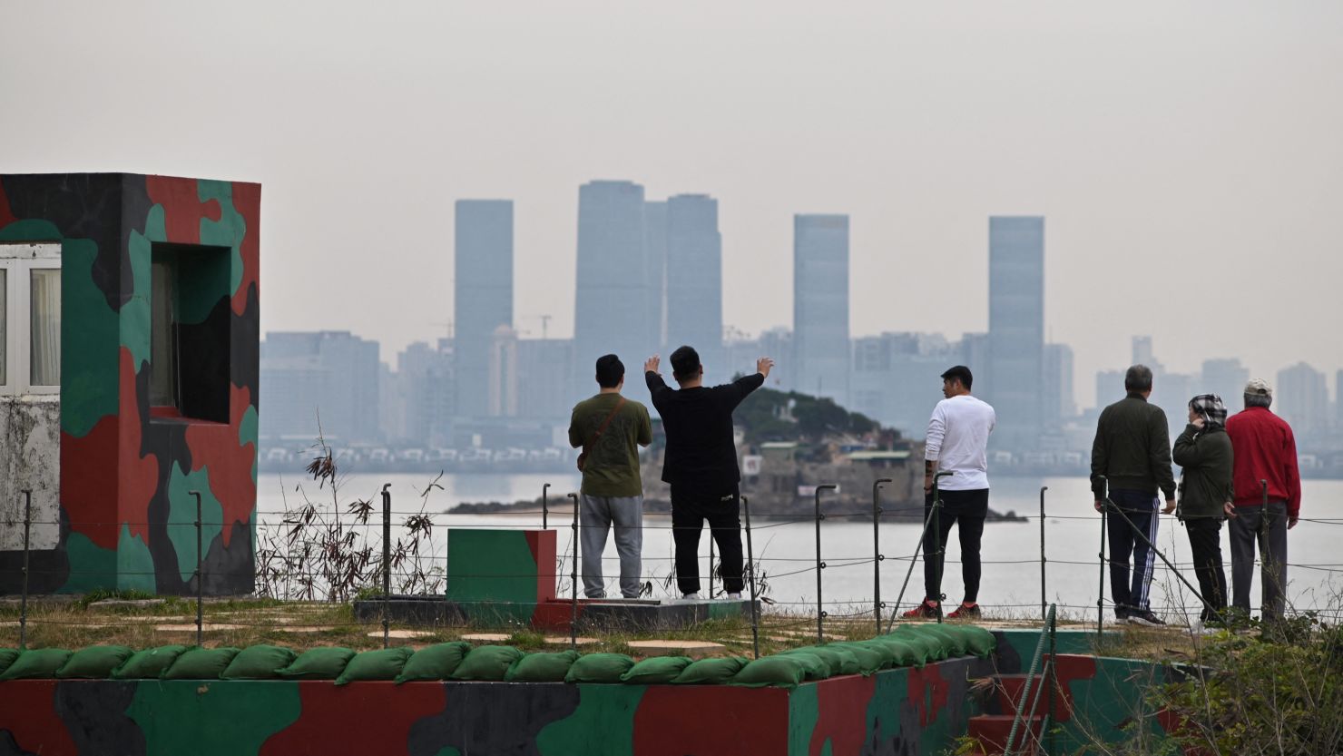 Tourists on Taiwan's Kinmen Island gaze at the Chinese city of Xiamen across the water on December 5, 2023.