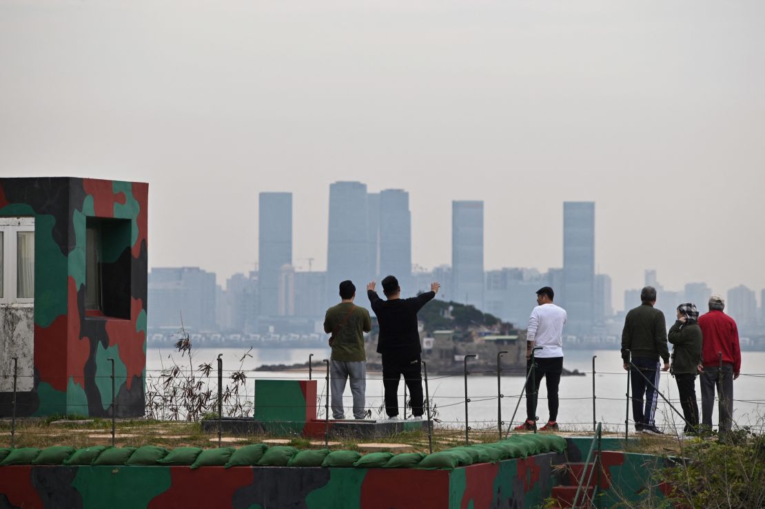 Tourists in Kinmen gaze at the skyline of Xiamen on December 5, 2023.
