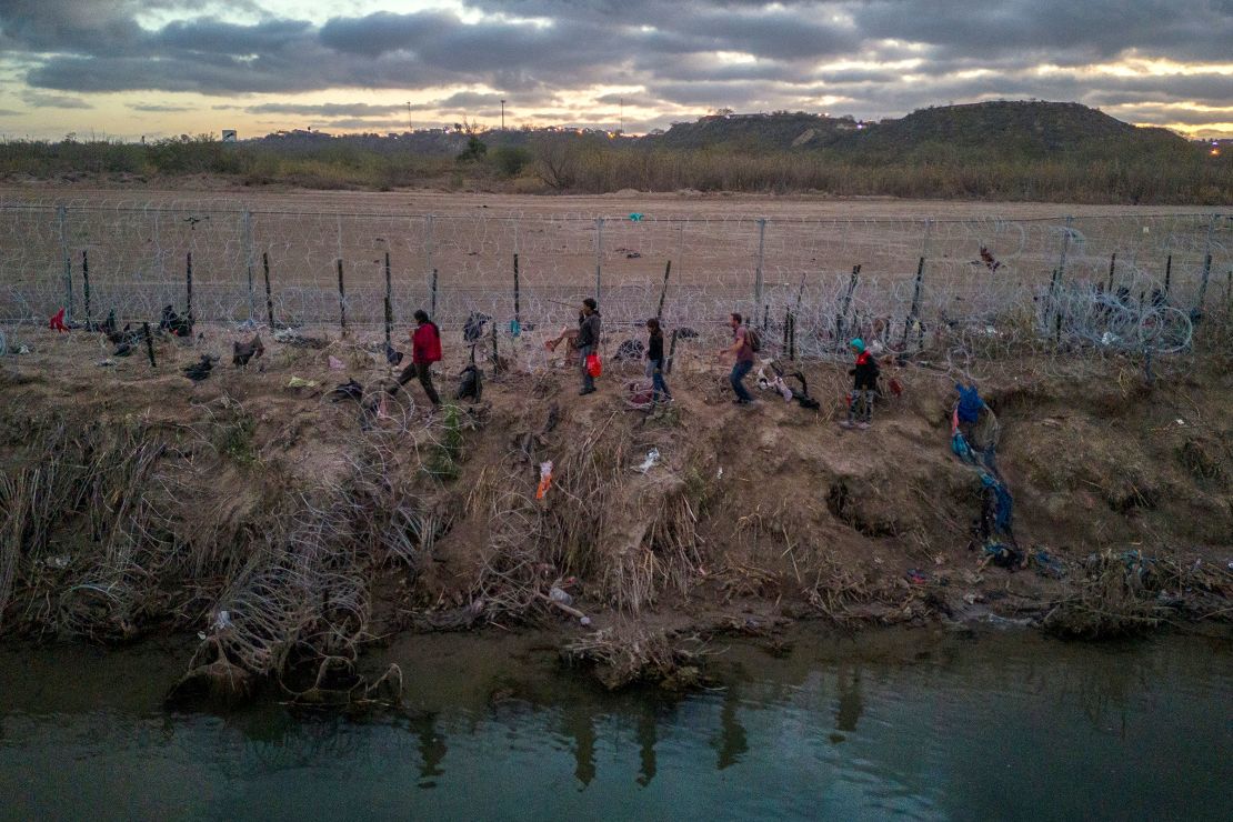 Migrants walk along razor wire after crossing the Rio Grande into the United States on January 8 in Eagle Pass, Texas.