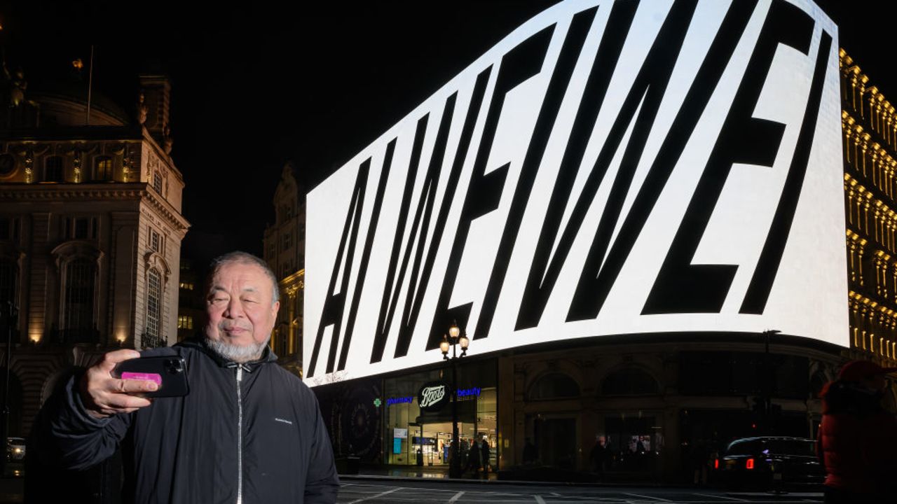 LONDON, ENGLAND - JANUARY 11: Artist Ai Wei Wei films himself as the first of 81 nightly presentations is displayed on a screen at Piccadilly Circus on January 11, 2024 in London, England.  Over 81 days – the length of time Ai Wei Wei was detained in a Chinese prison – the artist will pose 81 questions addressed to artificial intelligence (AI) and the wider public. Appearing every evening at 20:24 GMT on Piccadilly Lights, each question carefully considers the role of humankind's minds and actions in a fast-changing world, amid accelerating global crises and the rise of new technologies.  (Photo by Leon Neal/Getty Images)