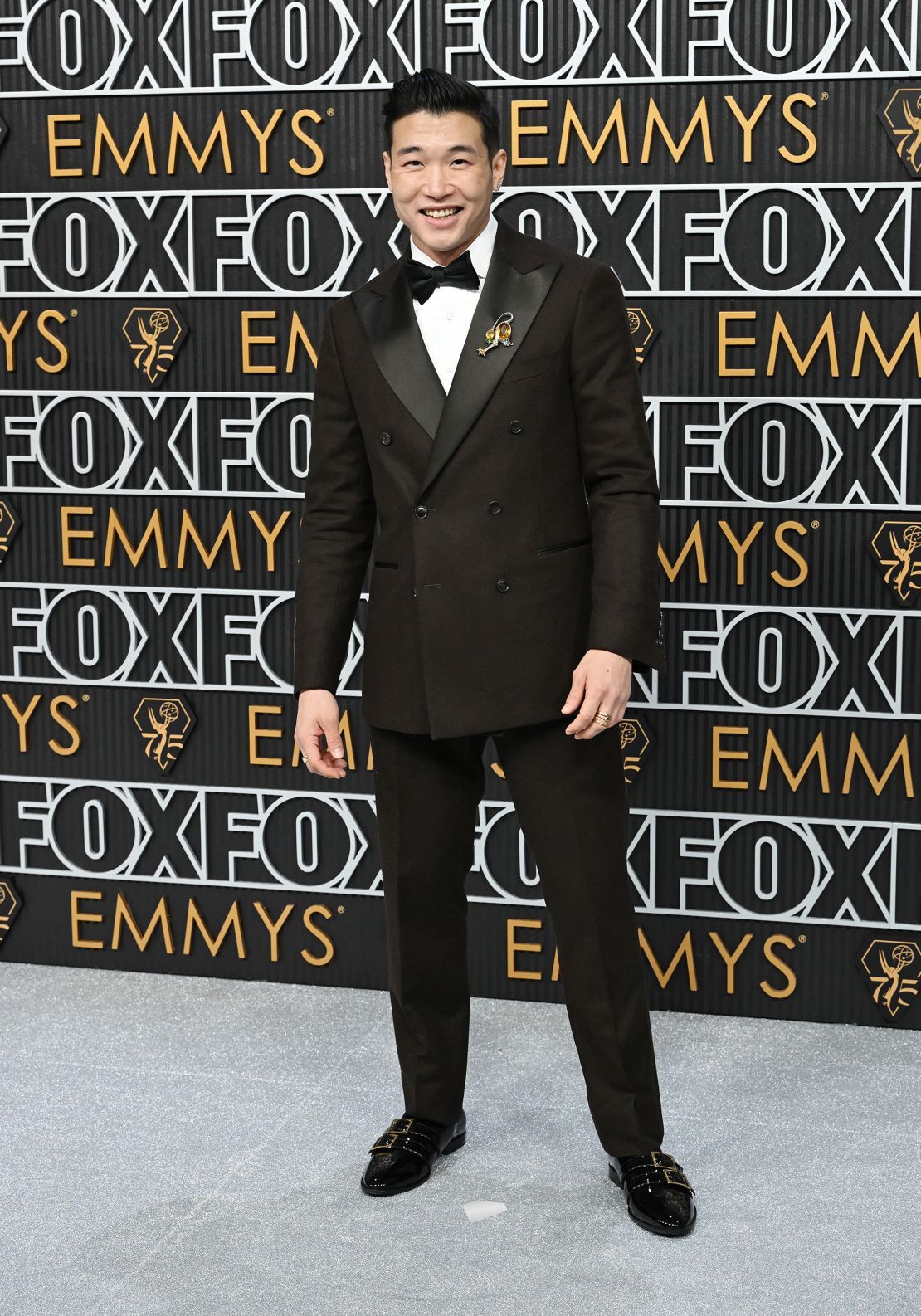 Joel Kim Booster, writer and star of "Fire Island," wore a double-breasted brown Italian wool suit by Todd Snyder with a bird brooch on his lapel.