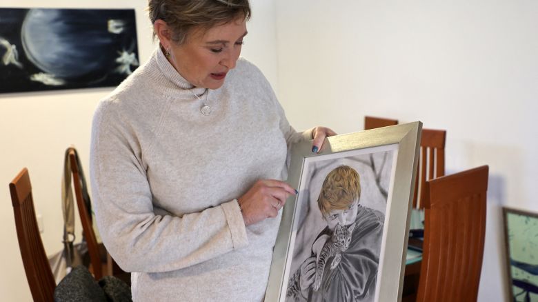 Iris Haim, the mother of hostage Yotam Haim, who was killed mistakly by Israeli soldiers a month ago in the Gaza strip, shows a portrait of her son, she received as a present, during an interview with AFP journalists in Shoeva, on the outskirts of Jerusalem, on January 15, 2024. Yotam Haim was gunned down in the Gaza Strip by Israeli soldiers who failed to realise he had escaped from the custody of his Hamas captors -- yet his mother refuses to criticise the army. Iris Haim, 57, feels the same way now as she did a month ago, when she sent an extraordinary message to the battalion involved in her son's killing. (Photo by GIL COHEN-MAGEN / AFP) (Photo by GIL COHEN-MAGEN/AFP via Getty Images)