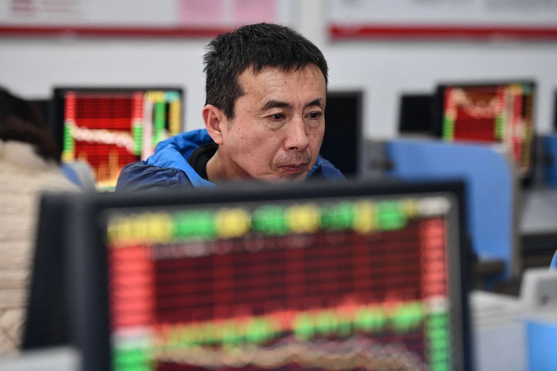 An investor looks at screens showing stock market movements at a securities company in Fuyang in China's eastern Anhui province on January 17, 2024.