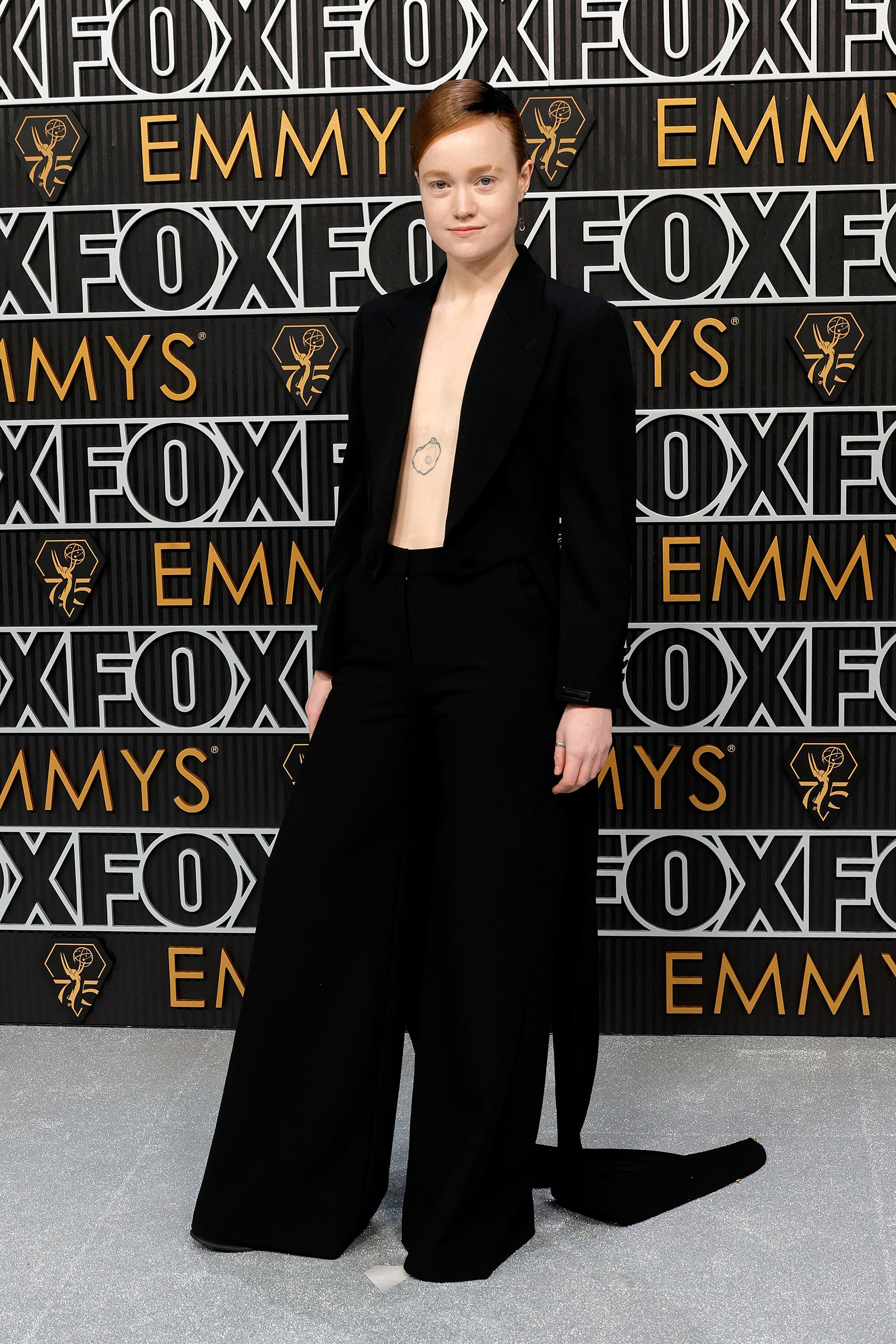 “Yellowjackets” actor's Liv Hewson, who opted out of gendered acting categories, showed off a pearl oyster tattoo, going shirtless in a black velveteen jacket with wide-leg pants and double train by Moschino. The star's jewelry was by State Property and Samsares.