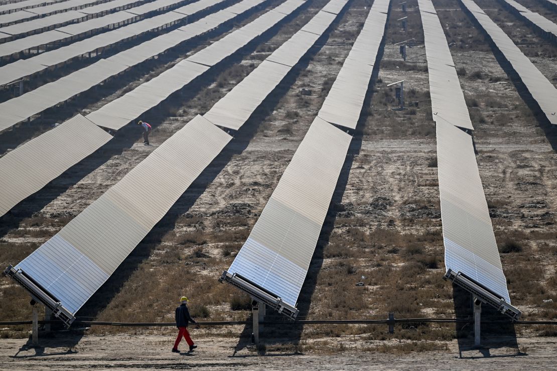 A worker walking past rows of solar panels at the Khavda Renewable Energy Park.