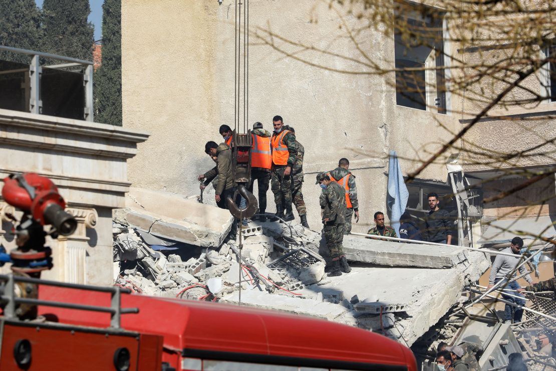 Security and emergency personnel search the rubble of a building destroyed in Damascus on January 20, 2024.