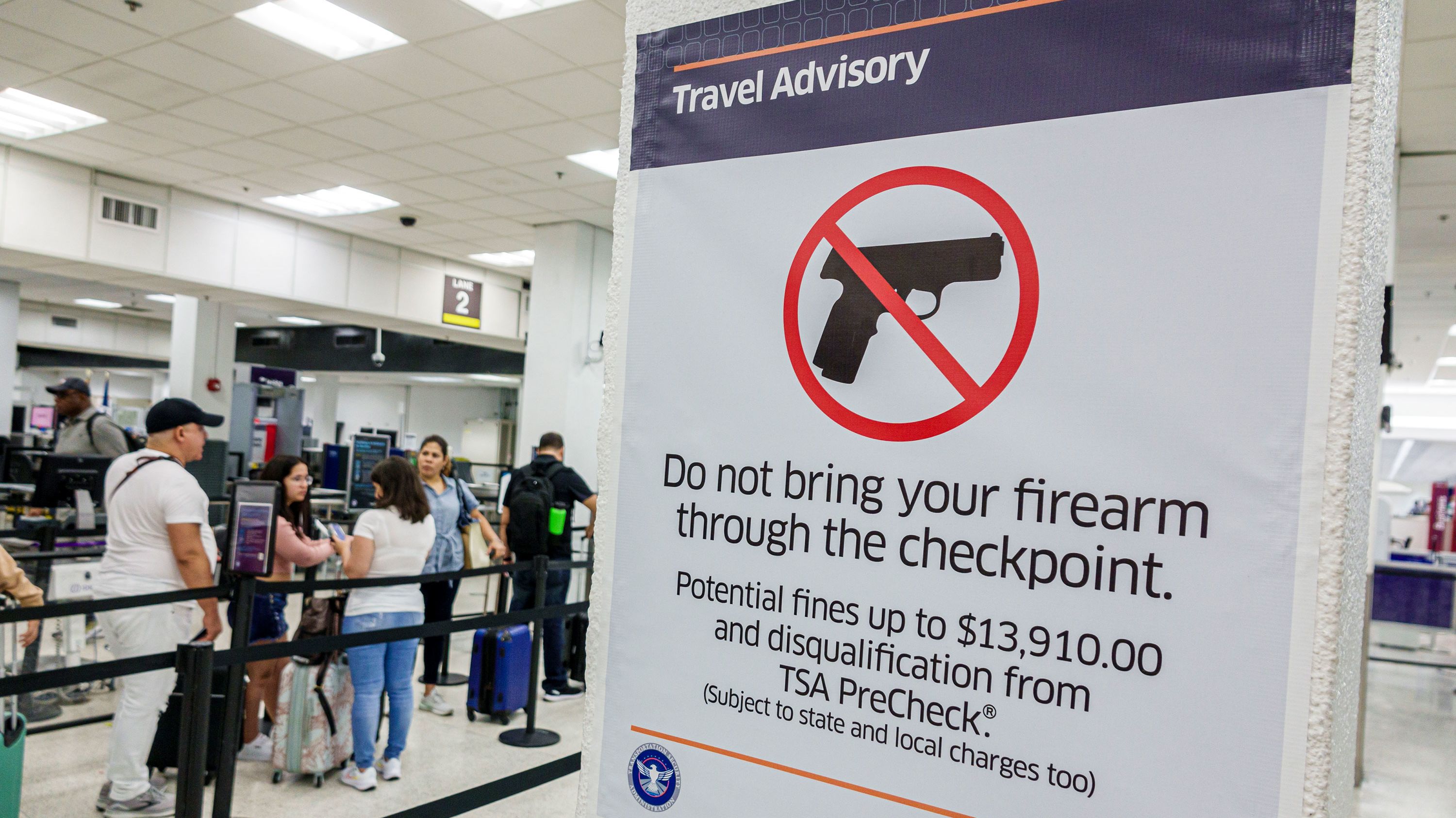 A sign at Miami International Airport's security screening lays out the consequences to people who try to bring a firearm through the checkpoint and get caught.