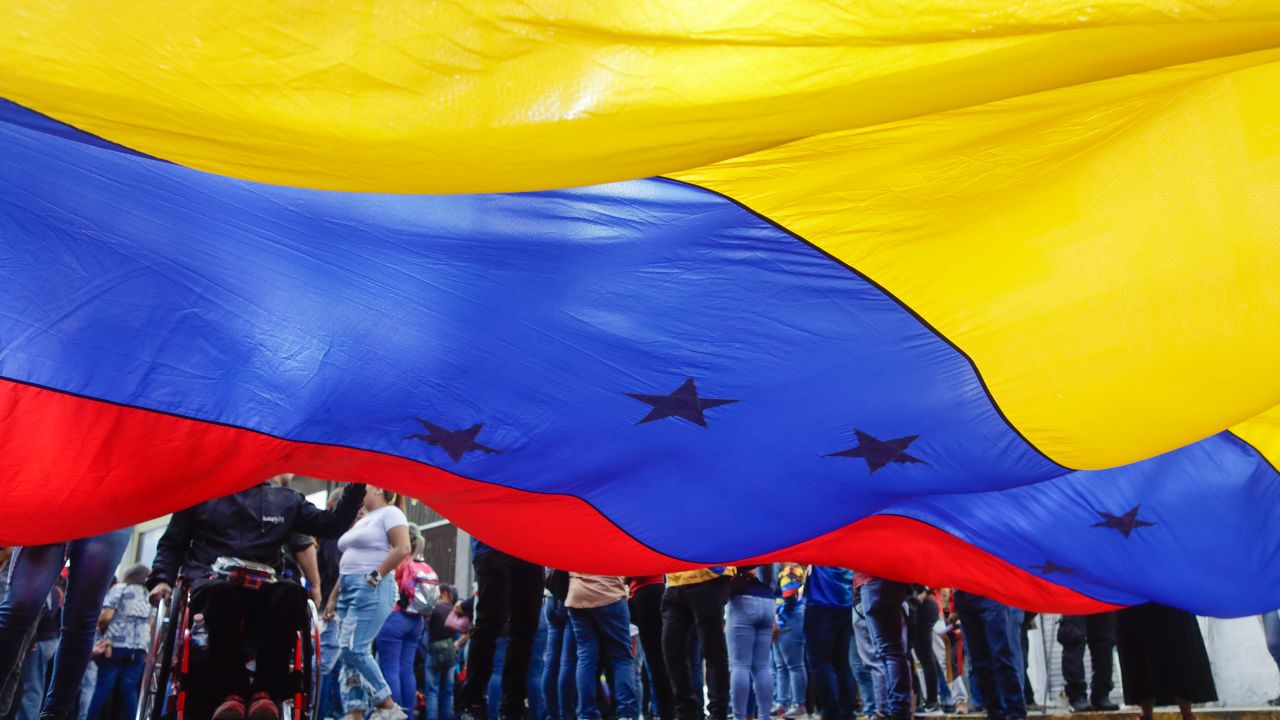 Simpatizantes del presidente de Venezuela, Nicolás Maduro, ondean una bandera venezolana gigante durante una marcha por el 65.º aniversario del derrocamiento del dictador Marcos Pérez Jiménez, el 23 de enero de 2024, en Caracas.