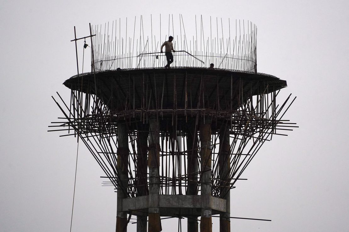 A construction worker carries metal rods during the construction of an elevated water tank in Ajmer, Rajasthan, on January 30, 2024.