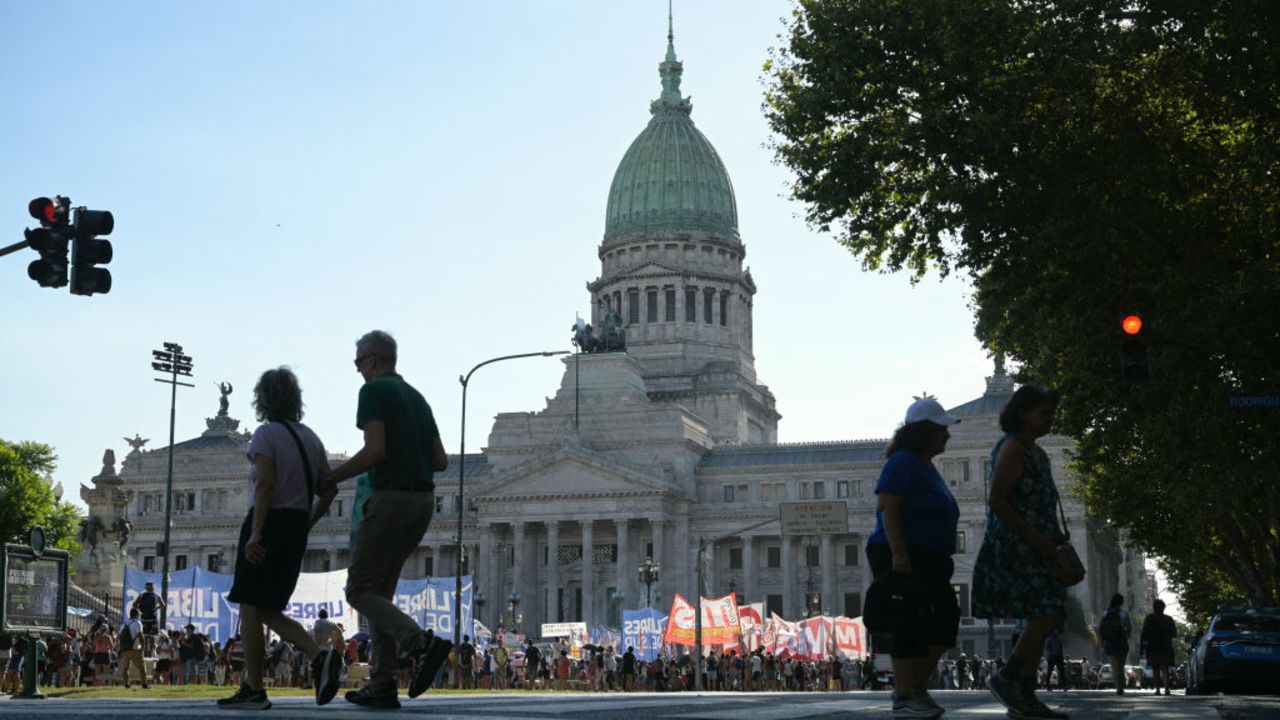 People cross the street near the Congress, and leftist parties protest while lawmakers debate the government's 'omnibus bill' of economic reforms in Buenos Aires on February 1, 2024. Argentina's Congress resumes debate on President Javier Milei's controversial ultra-liberal reform package after a tense day that left four people arrested during incidents between protesters and security forces outside parliament. (Photo by JUAN MABROMATA / AFP) (Photo by JUAN MABROMATA/AFP via Getty Images)