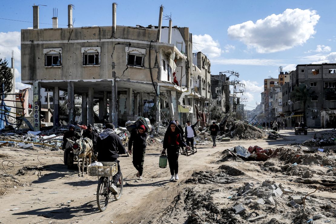 TOPSHOT - People walk past destroyed buildings in the Maghazi camp for Palestinian refugees, which was severely damaged by Israeli bombardment amid the ongoing conflict in the Gaza Strip between Israel and the Palestinian militant group Hamas, in the central Gaza Strip on February 1, 2024. (Photo by ANAS BABA / AFP) (Photo by ANAS BABA/AFP via Getty Images)