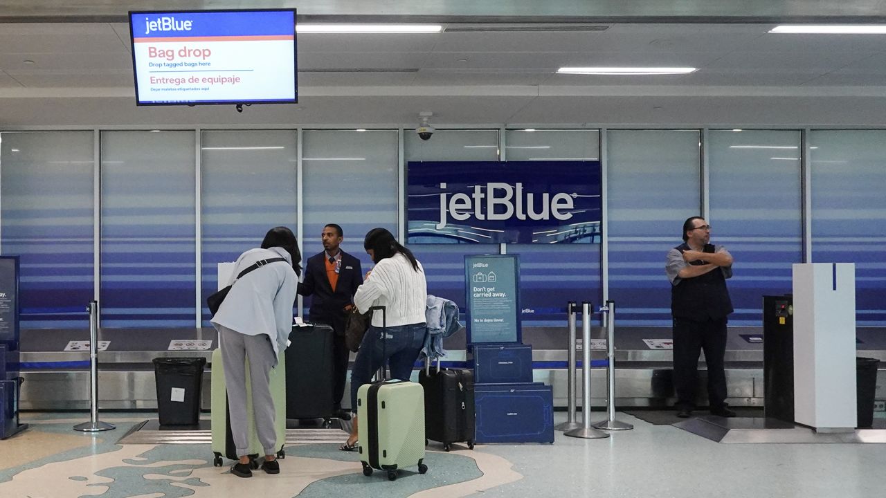People check in their bags at the JetBlue Airways counter in the Fort Lauderdale-Hollywood International Airport on January 31, 2024, in Fort Lauderdale, Florida. The company recently announced that it was considering implementing cost-cutting measures due to the forecasted decline in revenue and increase in costs.