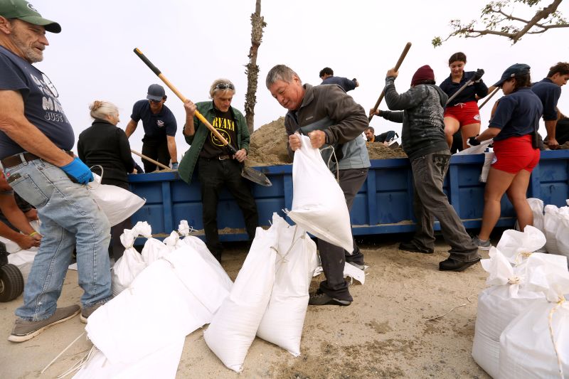Residents, with the help of lifeguards, collect bags of sand in preparation for the storm in Long Beach, California, on Saturday.