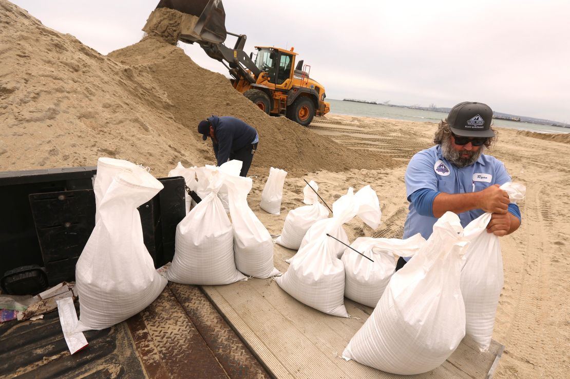 Ryan Coppenger, right, and Scott Larson, with the City of Long Beach Marine Bureau, collect bags of sand to be delivered to a lifeguard station that usually floods in preparations for an upcoming storm in Long Beach.
