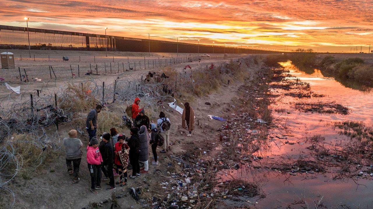 Immigrants wait next to razor wire after crossing the Rio Grande into El Paso, Texas on February 1, from Ciudad Juarez, Mexico.