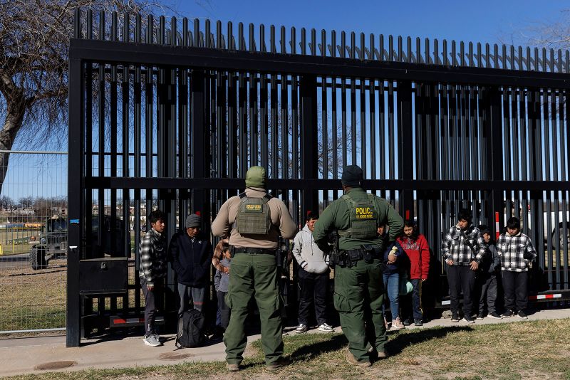 EAGLE PASS, TEXAS - FEBRUARY 4:  U.S. Border Patrol agents guard migrants that crossed into Shelby Park as they wait to be picked up for processing on February 4, 2024 in Eagle Pass, Texas. The Eagle Pass Police Department has barricaded all immediate streets leading to Shelby Park since Friday and only allows media or law enforcement to enter. Texas Gov. Greg Abbott has ordered the Texas National Guard to defy a Supreme Court ruling allowing federal Border Patrol agents complete access into the area which has seen high numbers of illegal crossings. (Photo by Michael Gonzalez/Getty Images)