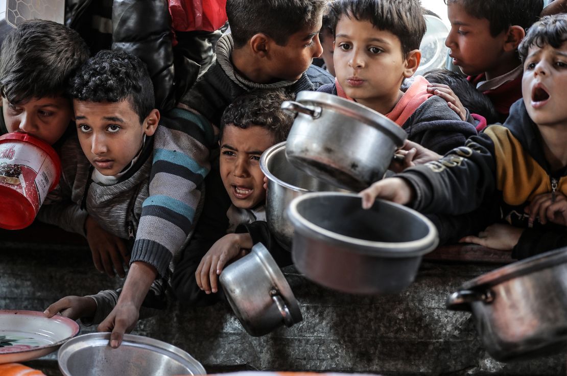 Children await food being handed out by aid organizations in Rafah.