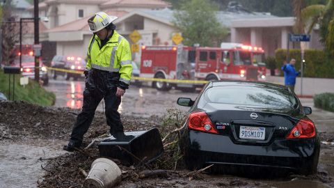 A firefighter walks near a vehicle stranded in a mud and rock during a storm in Los Angeles, California, US, on Monday, February 5, 2024.