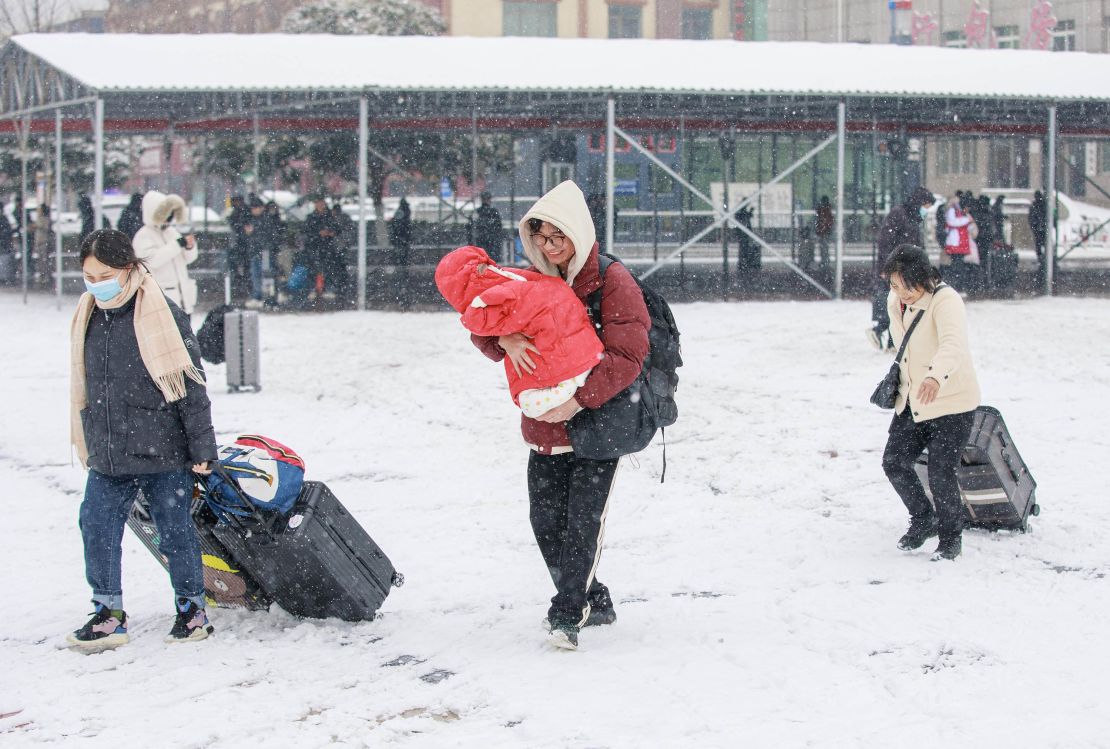 Travelers pull luggage through snow at Luohe Railway Station in Henan province on February 2.