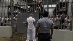 SAN VICENTE, EL SALVADOR - FEBRUARY 6: An inmate stands outside a cell as an officer stands on patrol at CECOT in Tecoluca on February 6, 2024 in San Vicente, El Salvador. On February of 2023 El Salvador inaugurated Latin America's largest prison as part of President Nayib Bukele's plan to fight gangs. Since then, the UN and NGOs have raised concern about the treatment of inmates, minors being held and suspects incarcerated as gang  without sufficient proof. Meanwhile, Bukele claims El Salvador's murder rate has fallen from the world's highest to the lowest in the Western Hemisphere. (Photo by Alex Peña/Getty Images)