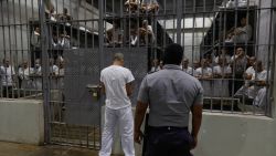 SAN VICENTE, EL SALVADOR - FEBRUARY 6: An inmate stands outside a cell as an officer stands on patrol at CECOT in Tecoluca on February 6, 2024 in San Vicente, El Salvador. On February of 2023 El Salvador inaugurated Latin America's largest prison as part of President Nayib Bukele's plan to fight gangs. Since then, the UN and NGOs have raised concern about the treatment of inmates, minors being held and suspects incarcerated as gang  without sufficient proof. Meanwhile, Bukele claims El Salvador's murder rate has fallen from the world's highest to the lowest in the Western Hemisphere. (Photo by Alex Peña/Getty Images)