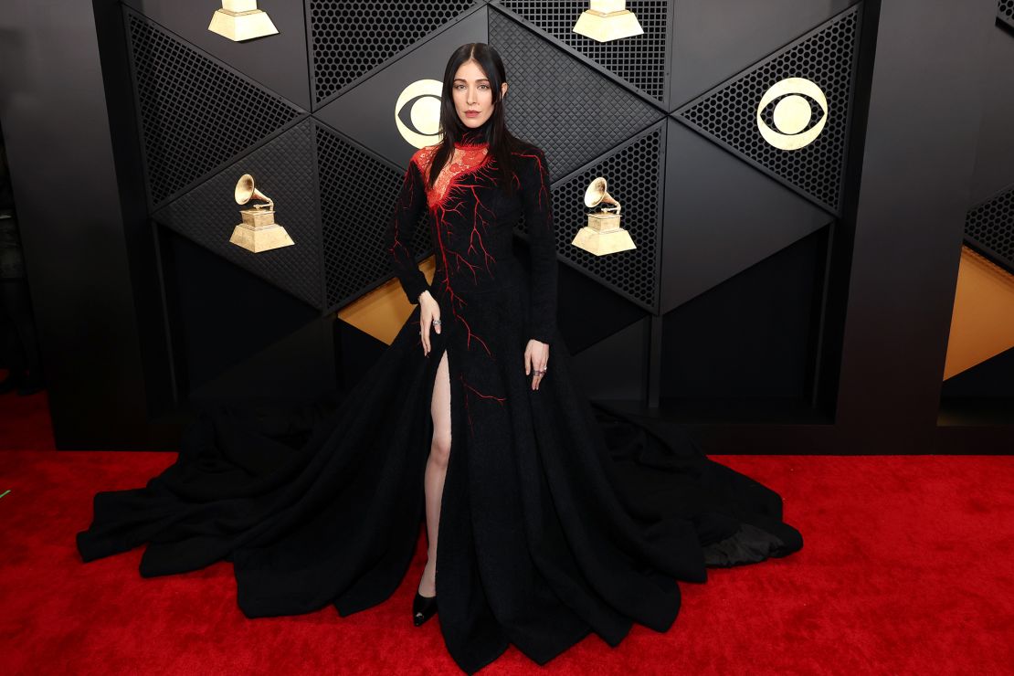 Singer Caroline Polachek brought some vampy glamour to the red carpet with a flared vintage Olivier Theyskens dress with red vein-like detailing and a lacy shoulder cut-out.