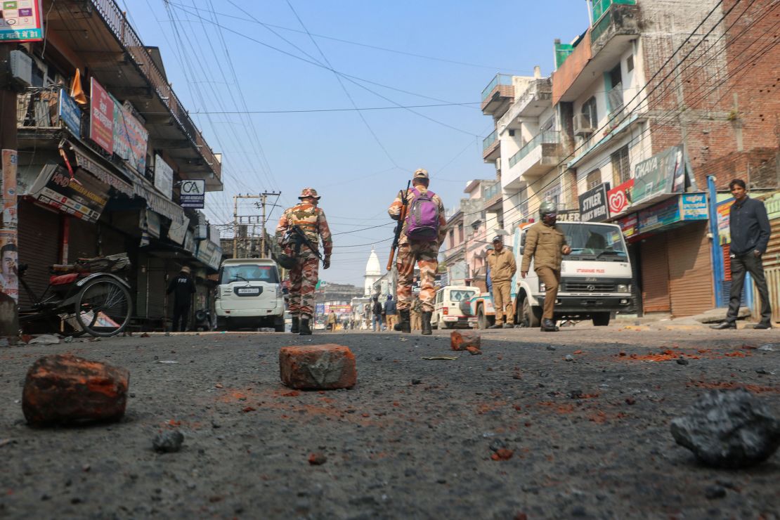Security walk past bricks and stones scattered on a road after day an Islamic school in Haldwani was destroyed in Uttarakhand on February 9, 2024.