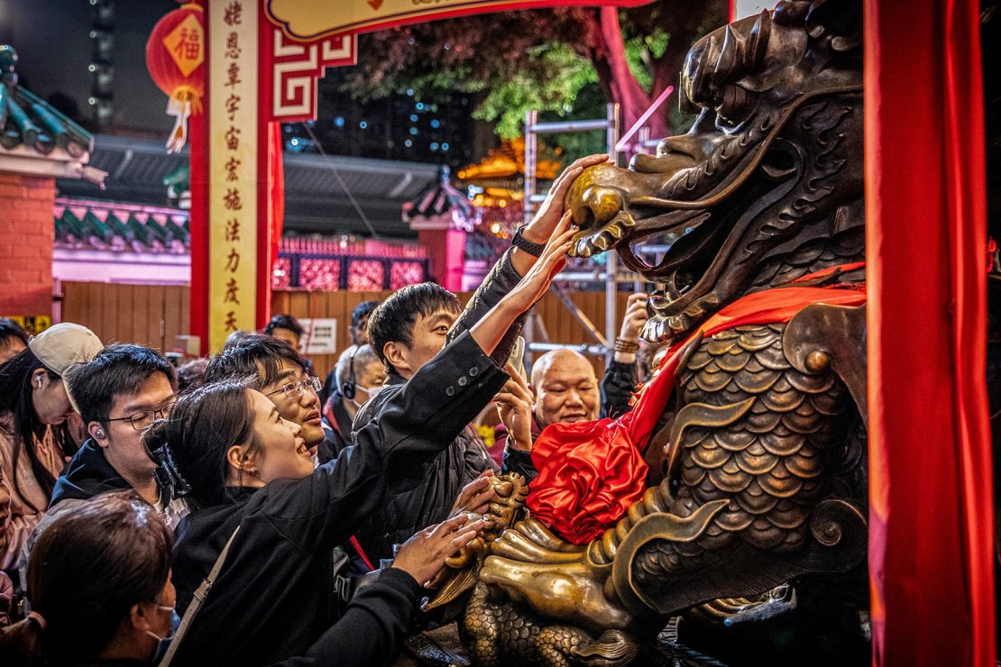 People gather in front of a dragon statue at the Wong Tai Sin Taoist temple in Hong Kong on February 9, 2024.