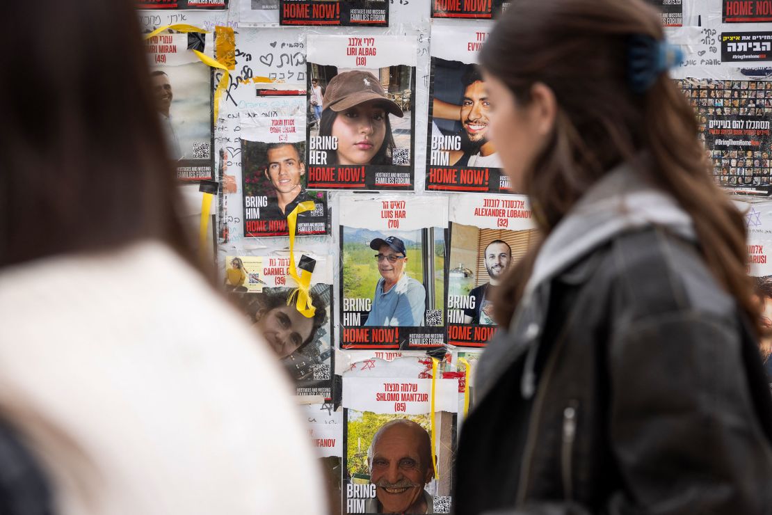 Pedestrians walk past posters of missing Israelis, including rescued hostage Louis Har (center, in blue shirt), on a wall at Hostages Square in Tel Aviv on February 12.